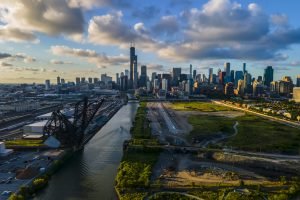 aerial drone shot of Chicago beautiful metropolis skyline during sunset along the river.  the cloud are vibrant with color as the city architecture
