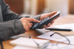 Closeup image of a businessman using calculator in a business meeting