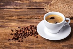 Coffee cup and beans on a wooden table. Dark background.