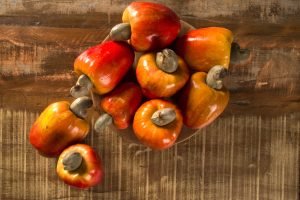 Some cashew fruit over a wooden surface.