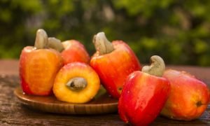 Some cashew fruit over a wooden surface.