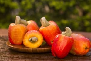 Some cashew fruit over a wooden surface.