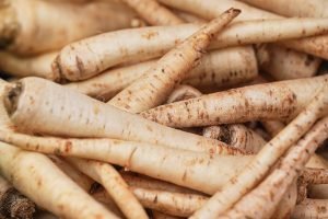 White parsnip or parsley roots displayed on street food market, closeup detail